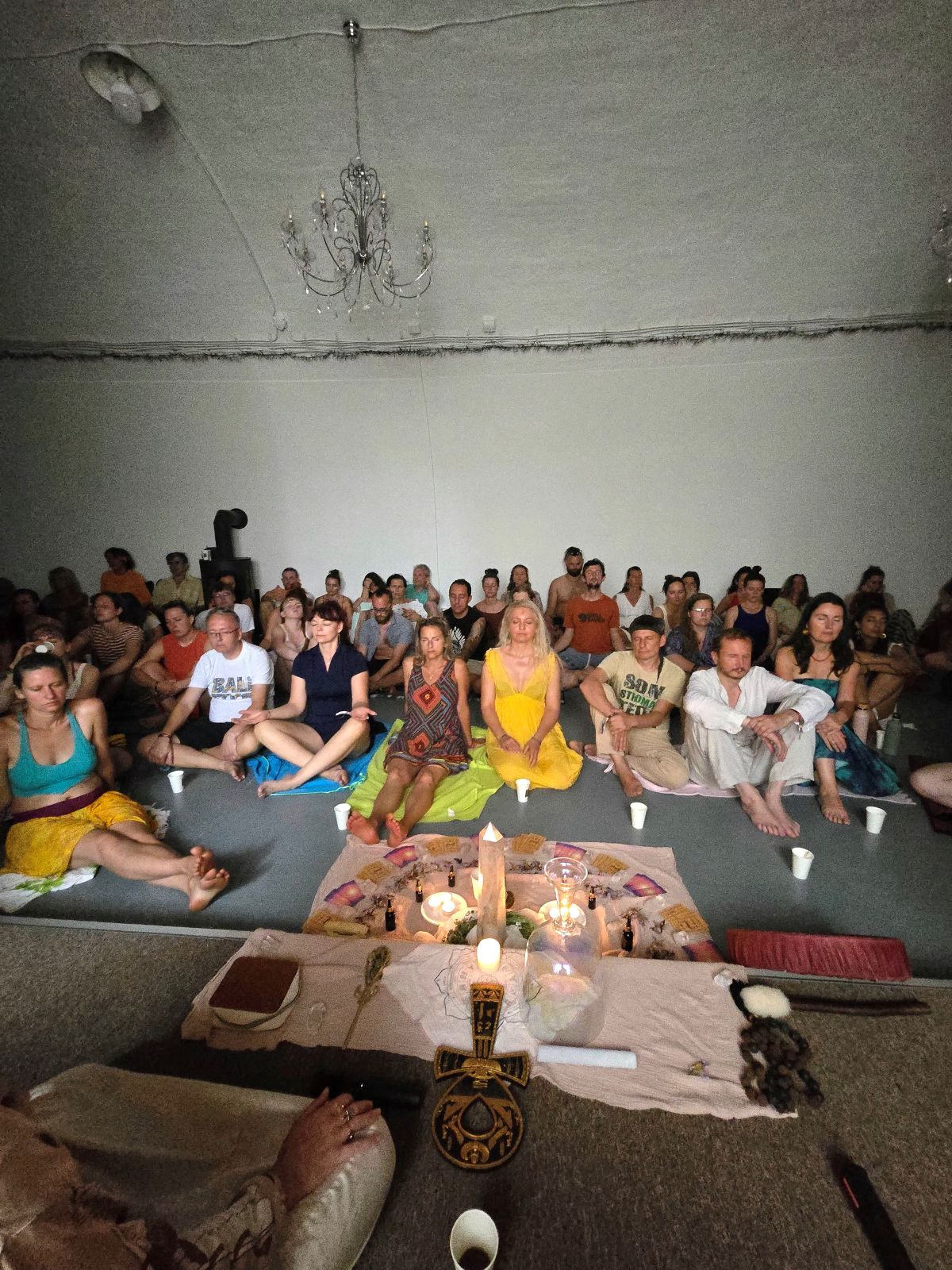 A full room seated in circle around a candlelit altar at a Blue Lotus ceremony.