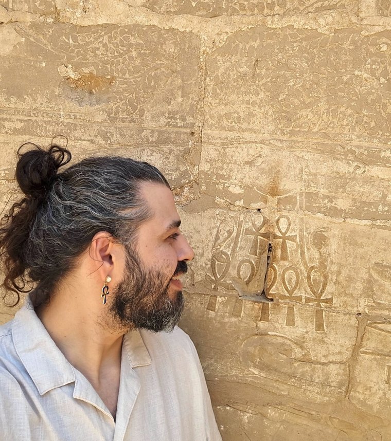 Ali beside ankh carvings on an Egyptian temple wall